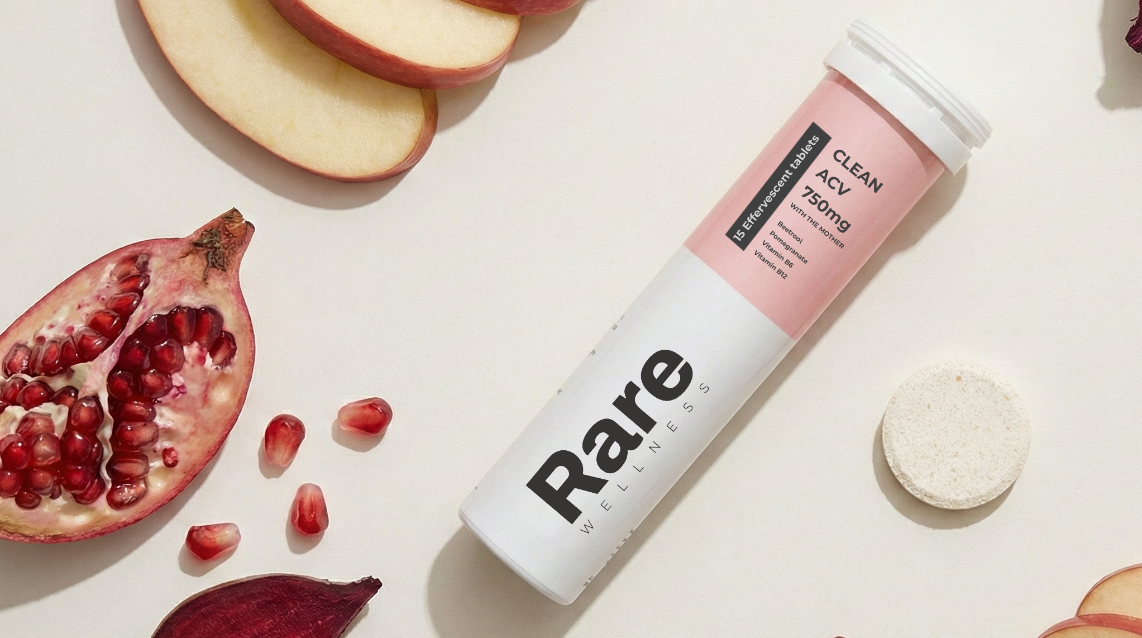 Tube labeled 'Rare' surrounded by sliced apples and pomegranates on a light background